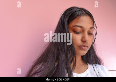 Porträt einer Frau vor rosa Hintergrund in nachdenklicher Stimmung Stockfoto