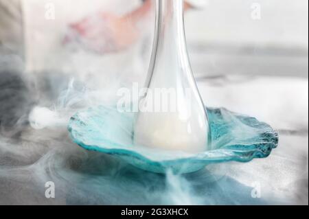 Feiner Restaurantkoch, der einen Teller mit raffinierten Küchenutensilien raucht. Stockfoto