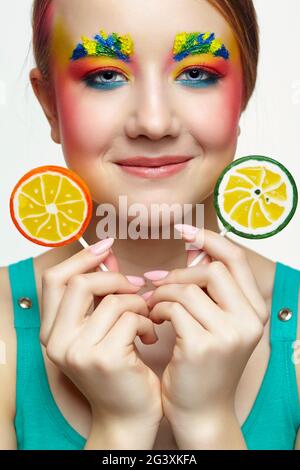 Teenager-Mädchen mit ungewöhnlichem Face Art Make-up und Lutscher in den Händen. Stockfoto