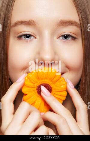 Teenager Mädchen mit Blume Lollipop in den Händen schließen Mund und lächeln. Stockfoto