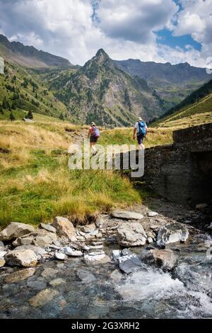 Wanderer auf einem Bergweg im Aure-Tal, in der Nähe von Tramezaigues, im Département Hautes Pyrenees (Obere Pyrenäen, Südwestfrankreich). Im Vordergrund Stockfoto