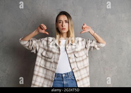 Confised junge Frau zeigt Finger auf sich selbst isoliert auf grauem Hintergrund Stockfoto