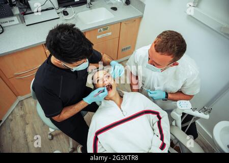 Kaukasische Patientin liegt auf dem Bett der Ärzte, während eine Krankenschwester operiert Stockfoto