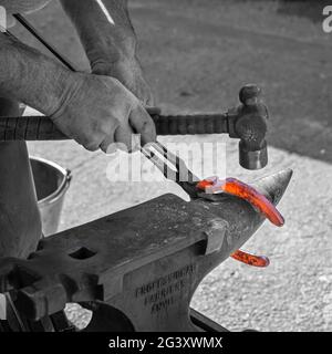 In Großbritannien arbeitet er am heißen Schuhschlagen eines Pferdes. Den beheizten Schuh hasten. Selektives Farbverfahren verwendet. Stockfoto