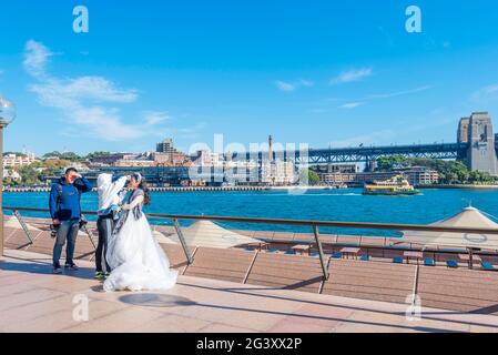 Eine Braut am Sydney Opera House und am Sydney Harbour in Australien bekommt ihr Make-up angepasst, während eine Fotografin geduldig wartet Stockfoto