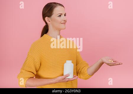 Angenehm aussehende europäische Modell hält Glas Pillen bieten Nahrungsergänzungsmittel Medikamente hat Ausdruck Raum für Promo zufrieden Stockfoto