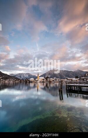 Blick über den winterlichen Tegernsee auf das Dorf Rottach-Egern mit der Kirche Sankt Laurentius, Bayern, Deutschland. Stockfoto