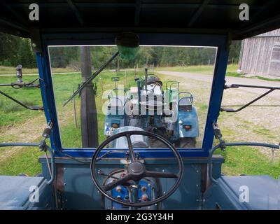 Innenansicht mit Blick durch die Windschutzscheibe eines restaurierten alten LANZ-Traktors in Grün mit karierten Sitzkissen in der Nähe der Kleinstadt Nesselwan Stockfoto