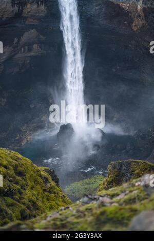 Nahaufnahme des Haifoss Wasserfalls in Südisland. Wasser stürzt gegen die Felsen am Boden und spritzt herum. Unschärfer Vordergrund Stockfoto