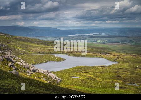 Sanfte grüne Hügel und Felder, die vom Sonnenlicht im Cuilcagh Mountain Park beleuchtet werden Stockfoto