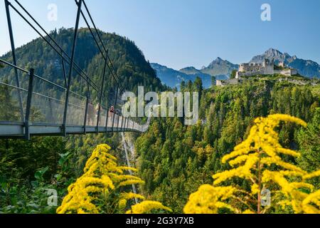 Mehrere Menschen laufen über die Seilbrücke Highline 179 mit der Burgruine Ehrenberg im Hintergrund, Reutte, Tirol, Österreich Stockfoto