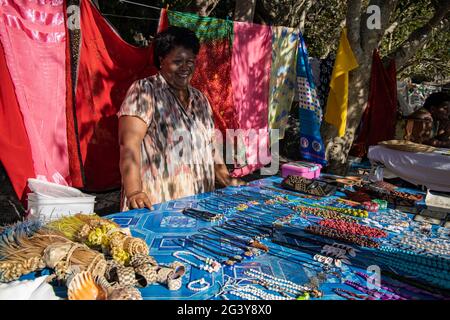 Lächelnde Frau mit Kunsthandwerk und Pareo-Handtüchern zum Verkauf an einem Souvenirstand am Strand, Sawa-i-Lau Island, Yasawa Group, Fidschi-Inseln, South Pacifi Stockfoto