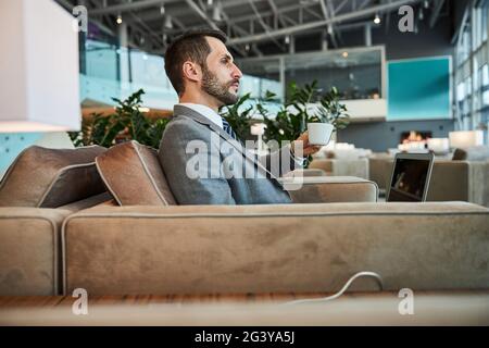 Nachdenklicher Blick auf einen ruhigen Geschäftsmann am Flughafen Stockfoto