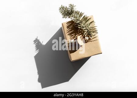 Geschenk in Bastelpapier auf einem weißen mit Schatten isoliert, weihnachten und Null Abfall, umweltfreundliche Verpackung. Ökologisches Weihnachtskonzept, Öko-Dekor Stockfoto