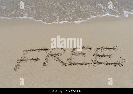 Kostenlose Emotion Großbuchstaben Handschrift in Sand auf dem Strand inspirierenden Hintergrund Stockfoto