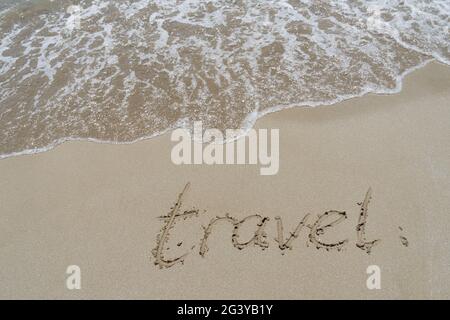 Reisehandschrift im Sand auf dem Hintergrund des Strandurlaubs Stockfoto