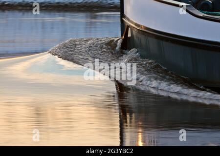 Frachtschiff im Winter an einem niederländischen Fluss bei Sonnenuntergang Stockfoto