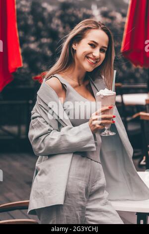 Eine Frauenhand hält einen erfrischenden Cocktail in einem Glas mit einer Tube. Stockfoto