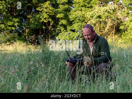 Magdeburg, Deutschland. Juni 2021. Wilko Florstedt vom Verein Wildtierretter Sachsen-Anhalt steuert eine Drohne vom Rand des Feldes aus. Es ist mit einer Wärmebildkamera ausgestattet, die zur Verfolgung von Rehkitzen verwendet wird. Dies verhindert, dass sie sich im Mäher großer Landmaschinen verfangen. Nach Angaben des Vereins Wildtierretter Sachsen-Anhalt e.V. sind in diesem Jahr bereits 200 Rehkitze vor dem Tod beim Grasschnitt gerettet worden. Quelle: Stephan Schulz/dpa-Zentralbild/ZB/dpa/Alamy Live News Stockfoto