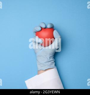 Hand in blauen Latex-Handschuhen mit rotem Herz, Spendenkonzept Stockfoto