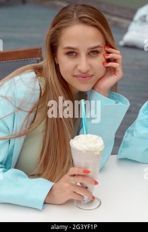 Eine Frauenhand hält einen erfrischenden Cocktail in einem Glas mit einer Tube. Stockfoto