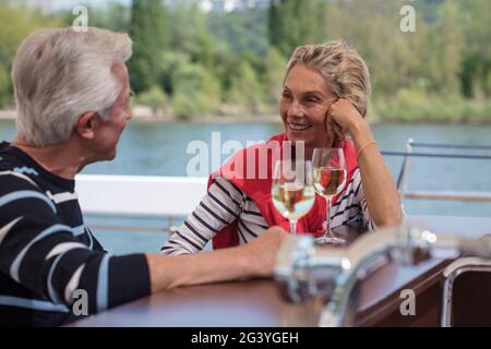 Das Paar genießt Weißwein auf dem Sonnendeck des Flusskreuzfahrtschiffes während einer Kreuzfahrt auf dem Rhein, in der Nähe von Koblenz, Rheinland-Pfalz, Deutschland, Europa Stockfoto