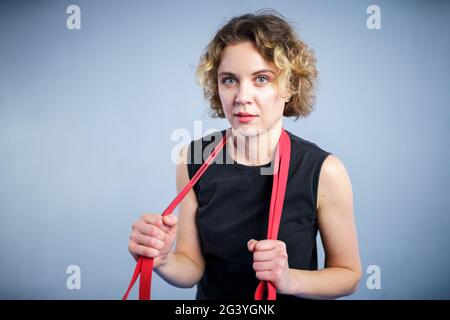 Sportlerin beim Training mit einem Widerstandsband. Schlanke Mädchen in guter Form. Menschen-, Sport- und Fitnesskonzept. Übungsbänder arbeiten Stockfoto