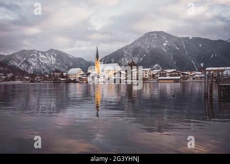 Blick über den winterlichen Tegernsee auf das Dorf Rottach-Egern mit der Kirche Sankt Laurentius, Bayern, Deutschland. Stockfoto