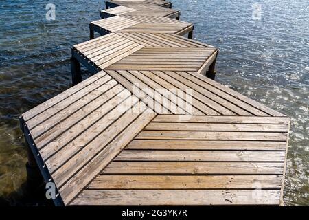 Eine Nahaufnahme aus einem tiefen Winkel abstrakte Ansicht eines Holzes Promenade und Pier, die in den Ozean führen Stockfoto