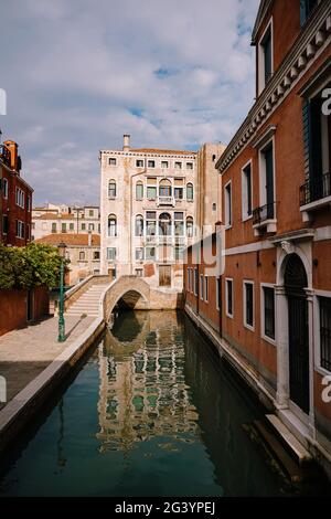 Ein schmaler Kanal in Venedig. Kleine Kanäle zwischen Häusern, ein paar Meter. Schöne kleine Brücken zwischen den Straßen. Stockfoto