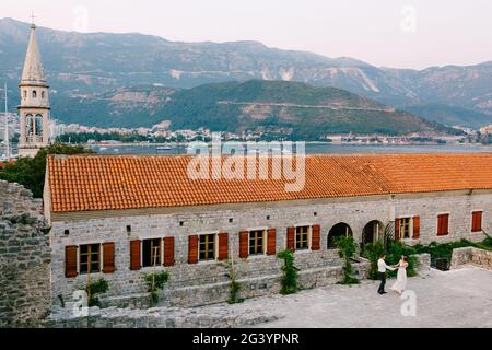 Die Braut und der Bräutigam wirbeln, halten Hände, in der Nähe der Kirche in der Altstadt von Budva Stockfoto