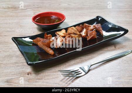 Knusprig gegrilltes Schweinefleisch in Scheiben mit würziger Sauce auf dem Teller Stockfoto