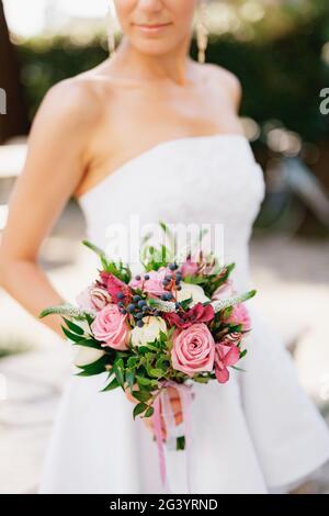 Eine raffinierte Braut, die einen Hochzeitsstrauß mit Rosen, veronica, Viburnum und Buchsbaum in der Hand hält, aus der Nähe Stockfoto