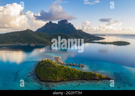 Luftaufnahme des Sofitel Bora Bora Private Island Resort mit Überwasser-Bungalows in der Lagune von Bora Bora mit Mount Otemanu bei Sonnenaufgang, Vaitape, Bora Bora, Stockfoto