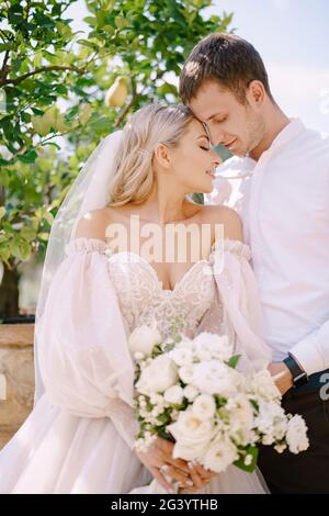 Hochzeitspaar im Garten. Der Bräutigam umarmt die Braut in der Nähe der Zitronenbäume. Hochzeit in Florenz, Italien, in einem alten Villa-Weingut. Stockfoto