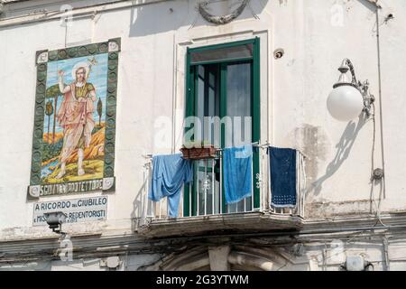 Vietri/Italien - 02.23.2019: Ein italienischer Balkon mit Handtüchern und Kleidung, die draußen hängen. Ein typischer und authentischer Blick von unten auf eine Hausfassade Stockfoto