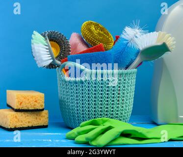 Blauer Kunststoffkorb mit Bürsten, Schwämmen und Gummihandschuhen zur Reinigung Stockfoto
