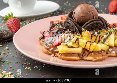 Herzwaffel mit Ananas und Erdbeere mit Gummy Candy und Eis darauf. Stockfoto