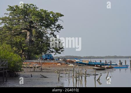 Gambia; in Bintang Bolong; Hafen im Dorf Bintang; Fischerboote am Ufer; Buschtaxi im Hintergrund wartet auf Passagiere Stockfoto