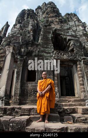 Buddhistischer Mönch steht stolz vor dem Bayon Tempel in Angkor Thom, Angkor Wat, in der Nähe von Siem Reap, Provinz Siem Reap, Kambodscha, Asien Stockfoto