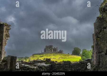 Blick durch die alten Ruinen der Hore Abbey Mauern auf der Burg Rock of Cashel mit dunklem, dramatischem Sturmhimmel Stockfoto