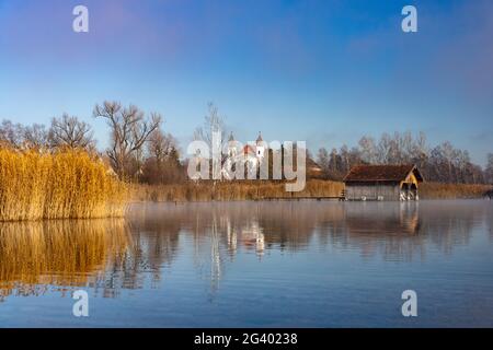 Bliock über die Kochelee nach Schlehdorf mit dem Kloster Schlehdorf und Fischerhütten am Ufer, Bayern, Deutschland. Stockfoto