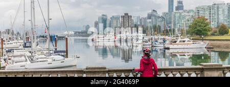 Vancouver Frau an der Skyline der Stadt trägt Helm Radfahren im Hafen vor dem städtischen Hintergrund Panorama-Banner. Stockfoto