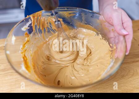 Der Prozess der Herstellung von Creme für Schokoladenkuchen. Stockfoto