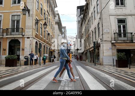 Lissabon, Portugal. Juni 2021. Menschen mit Gesichtsmasken gehen am 18. Juni 2021 auf einer Straße im Zentrum von Lissabon, Portugal. Die portugiesische Regierung hat am Donnerstag beschlossen, die Verbreitung von Covid-19 in den Großraum Lissabon am Wochenende ab 3 Uhr am Freitag zu verbieten, da die Zahl der Fälle in Teilen des Landes zugenommen hat. Quelle: Pedro Fiuza/ZUMA Wire/Alamy Live News Stockfoto