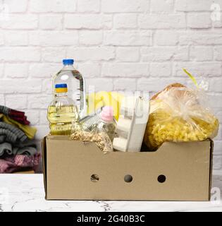 Karton mit verschiedenen Produkten, Obst, Nudeln, Sonnenblumenöl in einer Plastikflasche und Konservierung Stockfoto