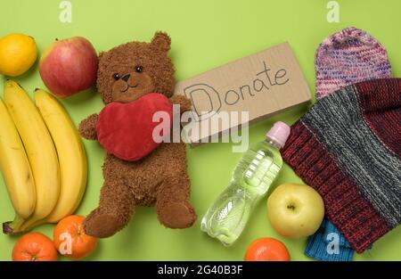 Kleidung und brauner Teddybär auf grünem Hintergrund, Draufsicht Stockfoto