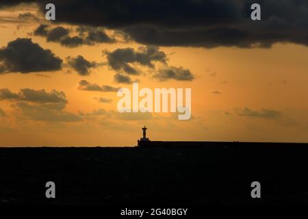 Leuchtturm Silhouette dunkler Himmel bei Sonnenuntergang. Kontrastierende abendliche Meereslandschaft. Bedrohliche Wolken hingen über dem Meer. Das Konzept der Elemente, Depression, schlecht Stockfoto