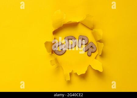 Das Wort GDPR in einem zerrissenen Loch mit gelbem Hintergrund. Draufsicht Stockfoto