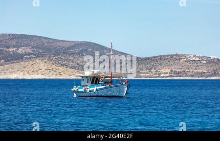 Traditionelles altes Holzboot, das auf ruhigem Wasser vor Anker liegt. Typisches farbenprächtiges Fischerboot, das auf offenem Meer vor der Küste der Insel iOS festgemacht ist. Kykladen, Griechenland. S Stockfoto